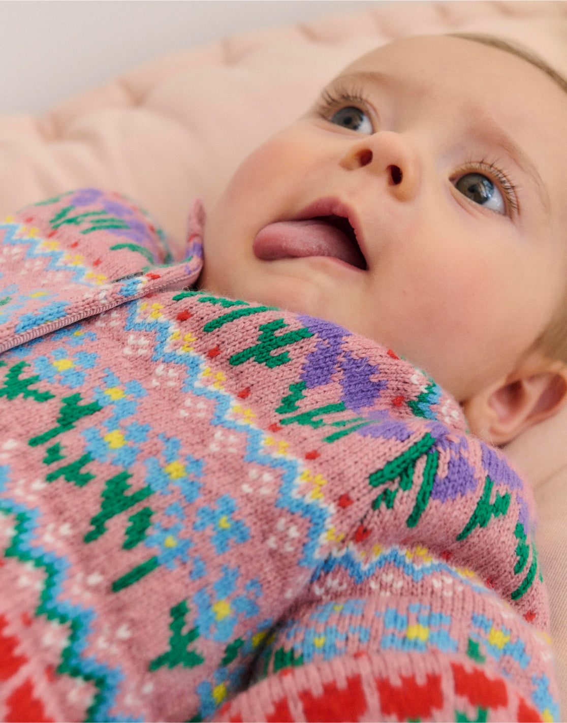 Baby lying down wearing Boden fair isle knit