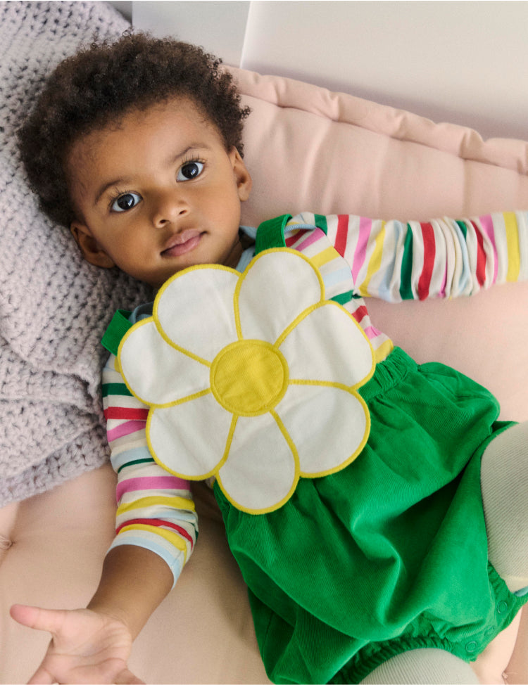 Baby lying down, wearing Boden novelty flower romper