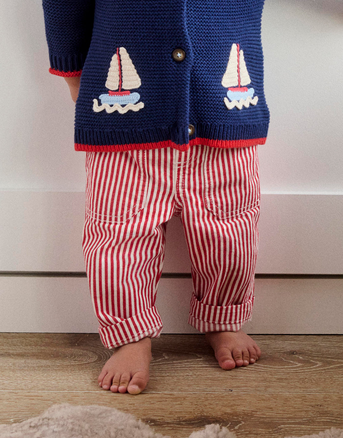 Baby's legs wearing red and white striped Boden trousers