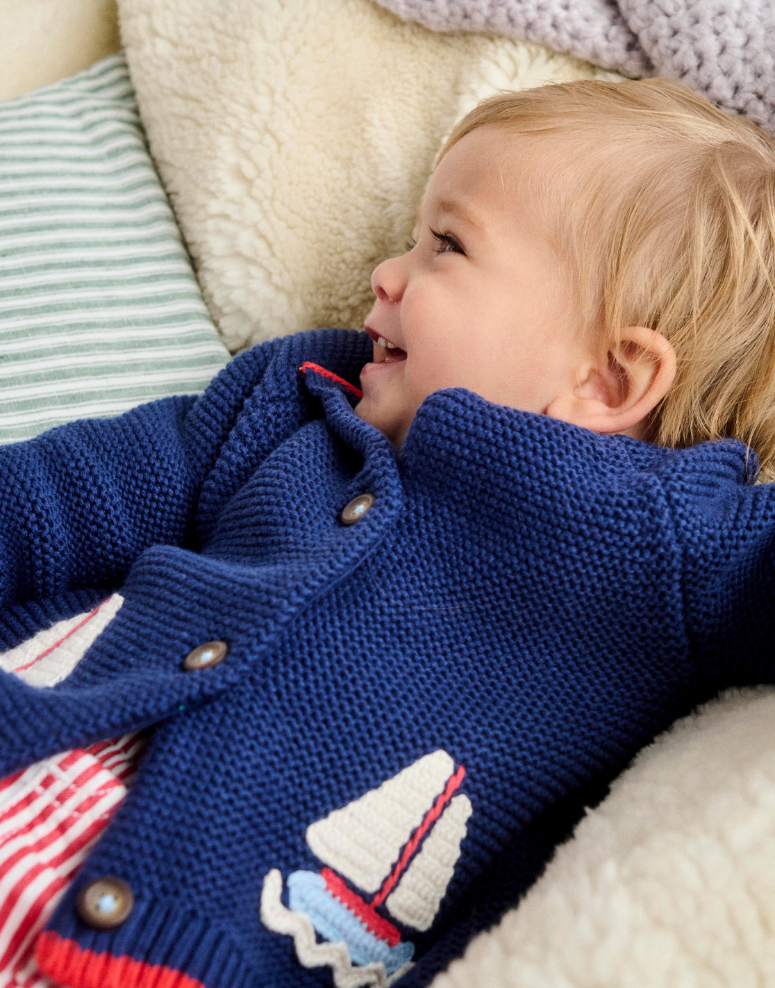 Baby lying down wearing Boden nautical knit