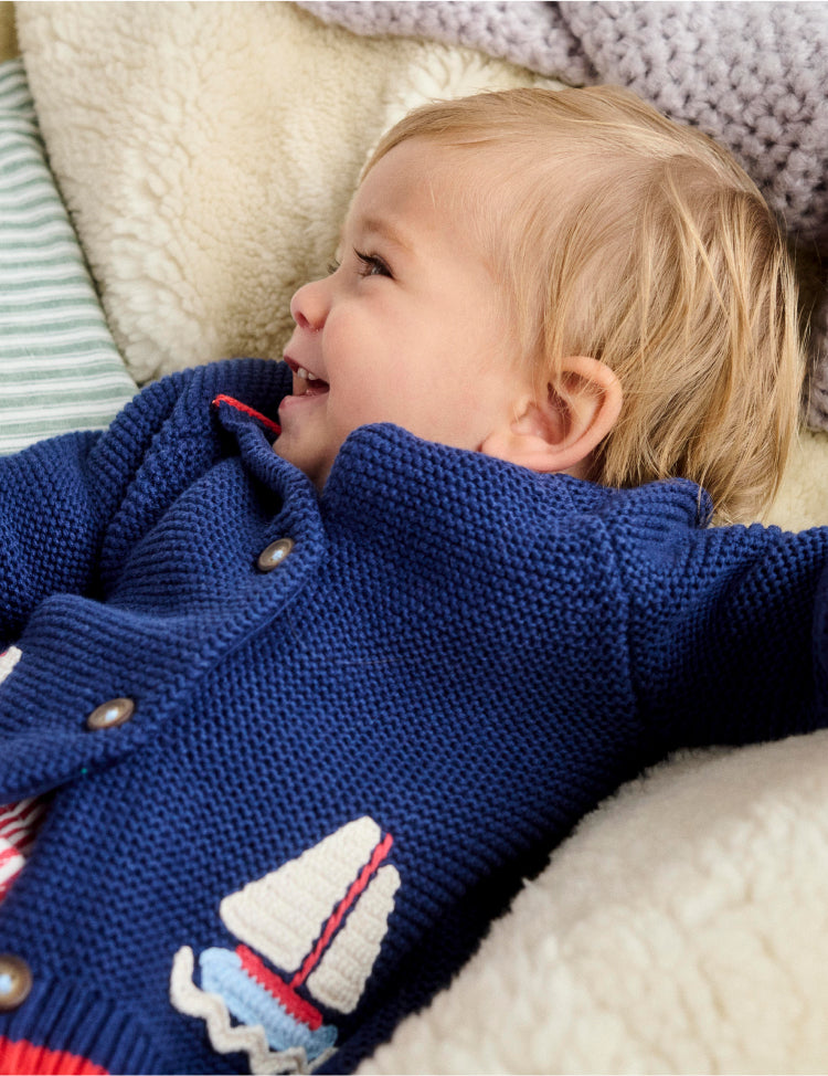 Baby lying down wearing Boden nautical knit