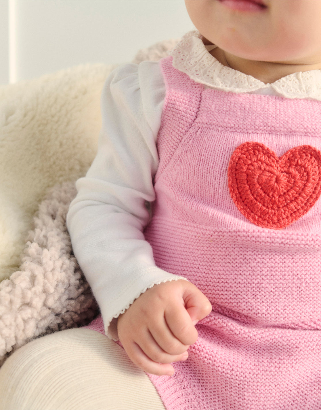 Close up of baby wearing a pink love heart Boden romper