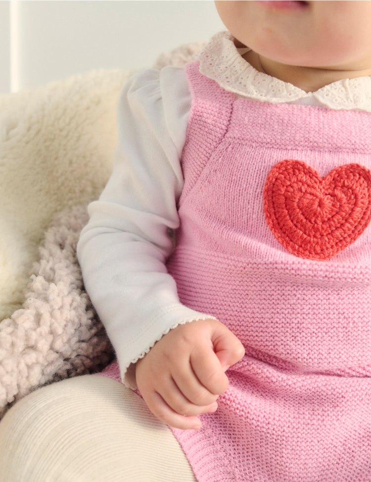 Close up of baby wearing a pink love heart Boden romper