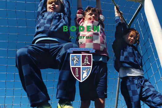 Drei Kinder spielen hinter einem Fußballtor mit dem „Boden“-Logo.
