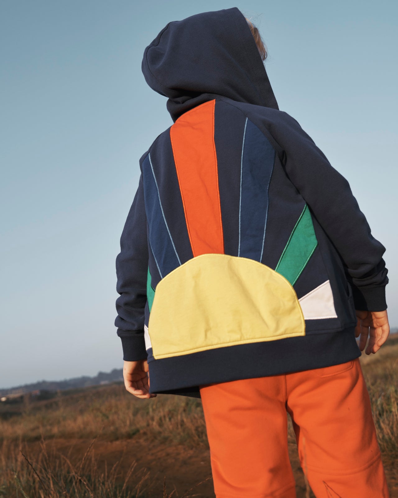 Boy in a field, showing the back of a Boden hoodie