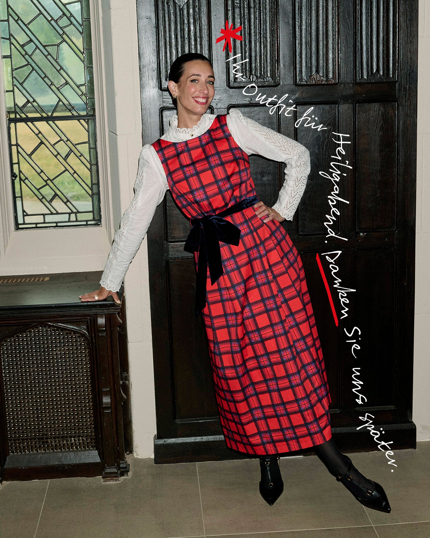 Frau in einem roten Karokleid mit schwarzer Schleife, die vor einer Tür steht.