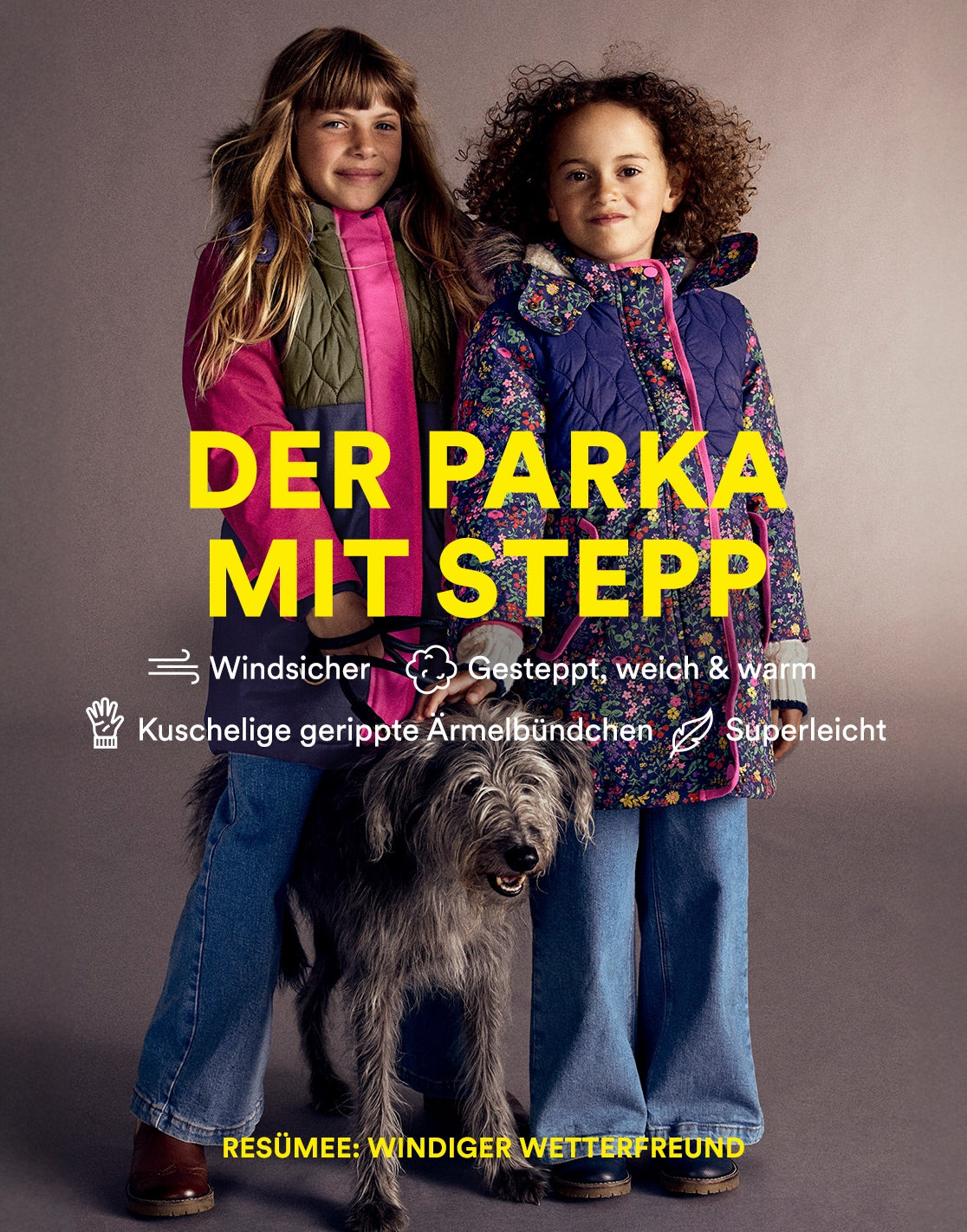 Zwei junge Mädchen in Jacken stehen neben einem Hund, beide tragen Kleidung von Boden.