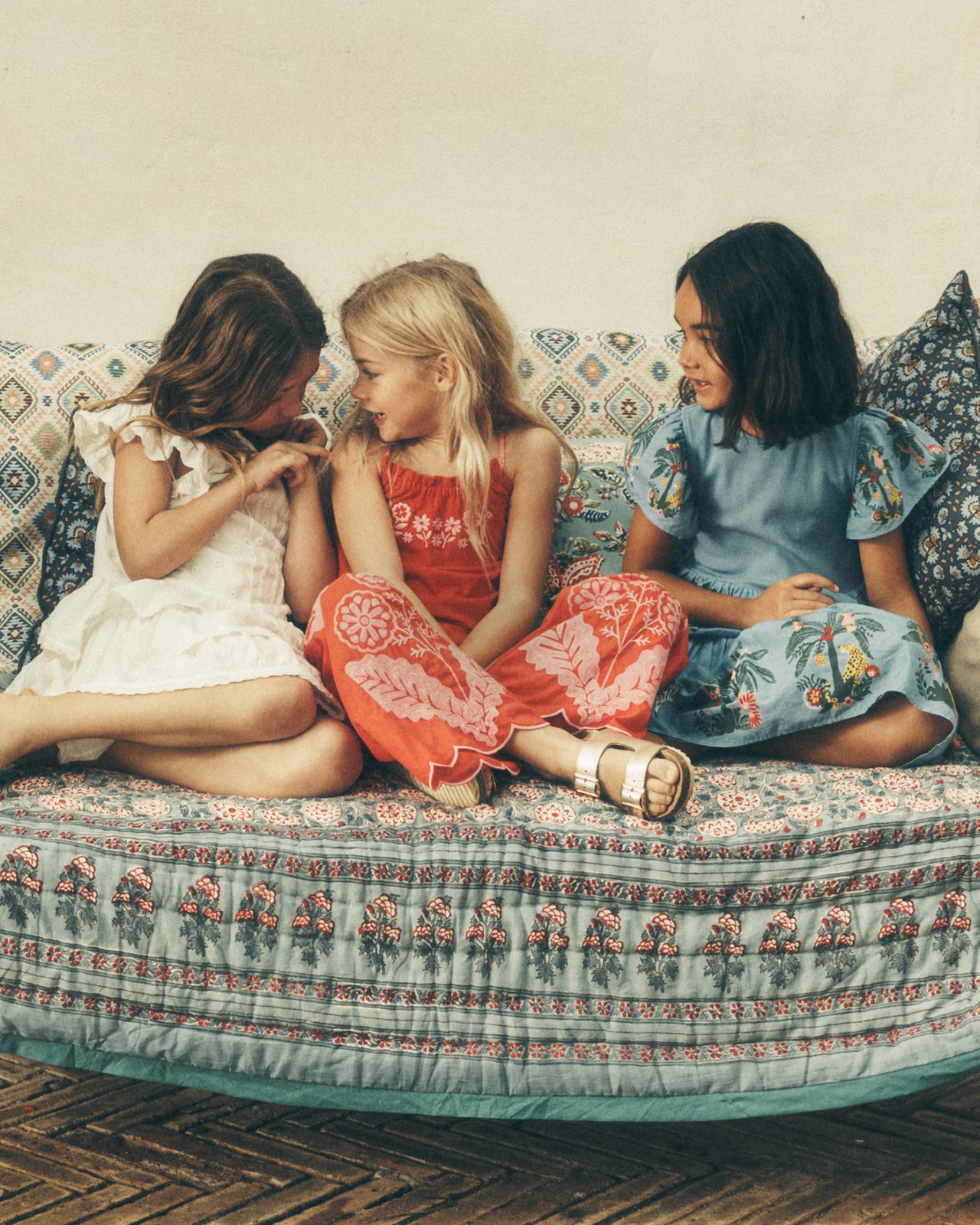 Drei Kinder, die auf einem Sofa sitzen und miteinander reden