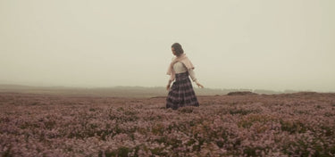 Person, die in einem Feld voller rosa Blumen mit nebligem Hintergrund steht