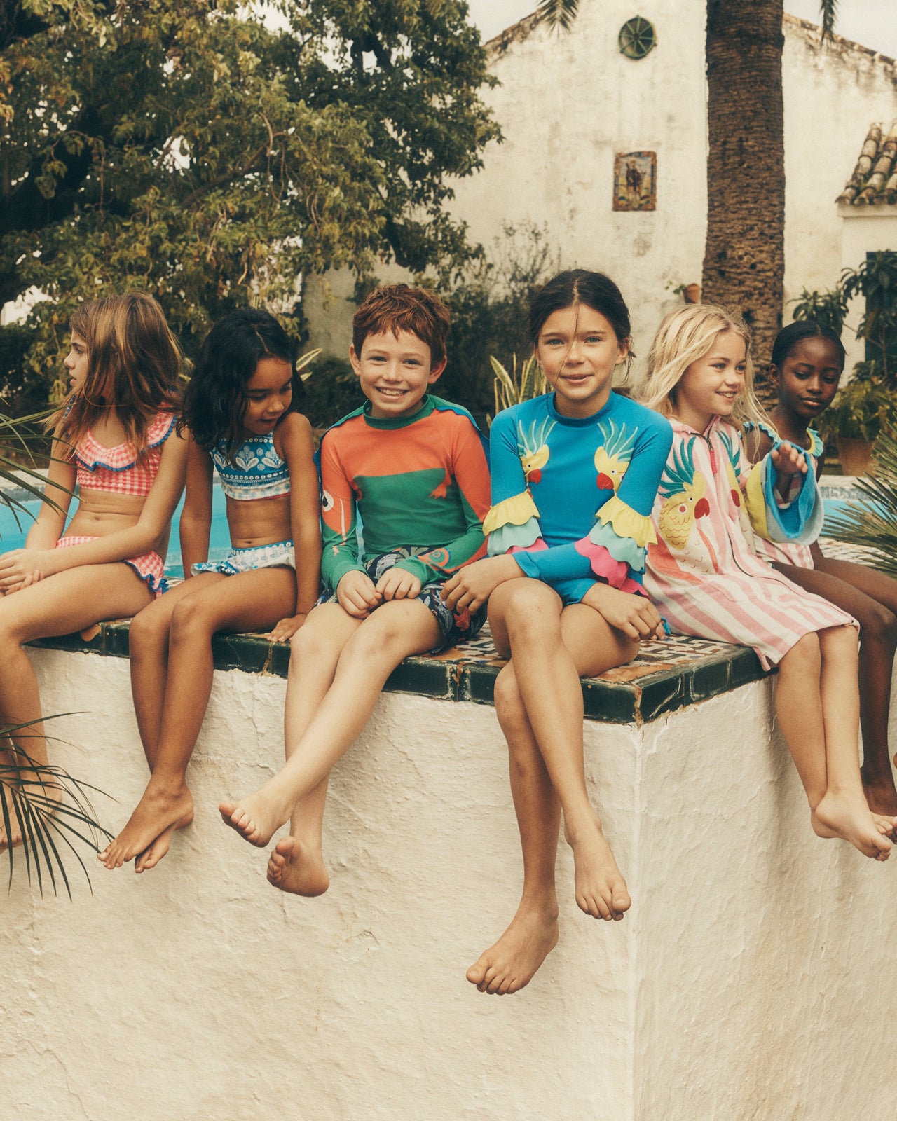 Children sitting on a ledge outdoors with promotional text overlay