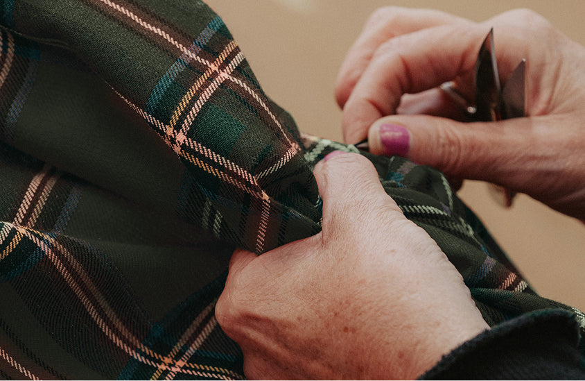 Frau, die Tartan-Stoff näht